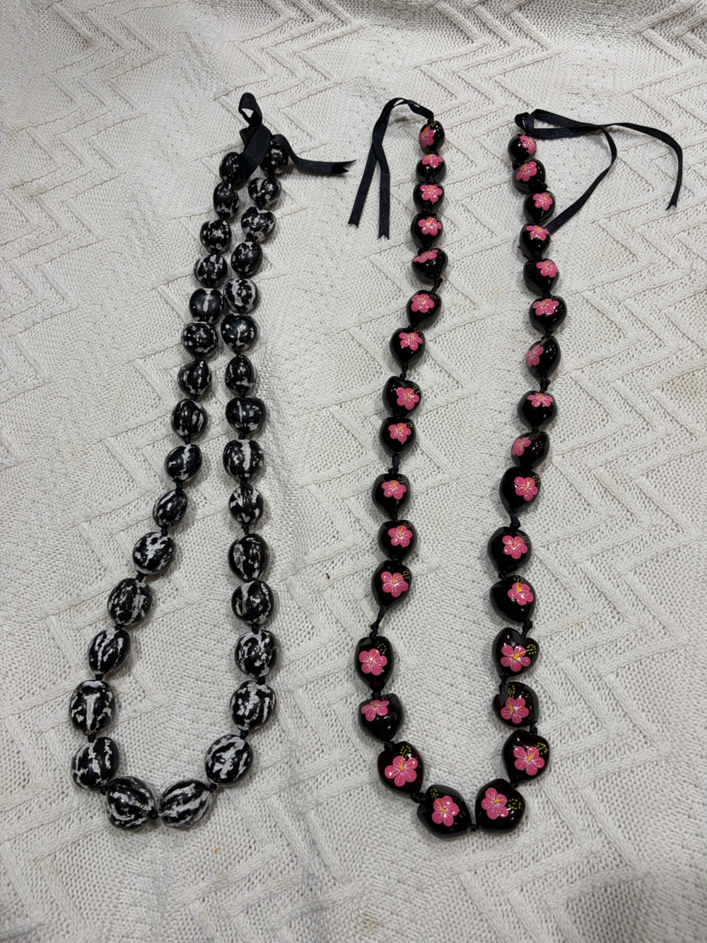 Two Hawaiian kukui nut leis black with pink flower/ black and white graduation